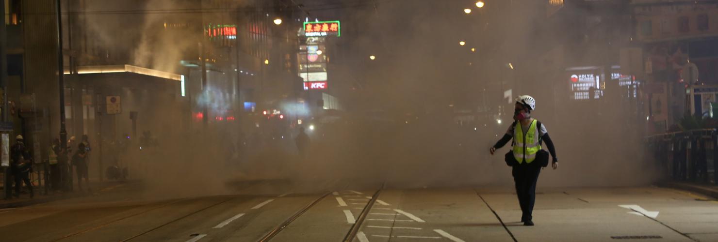 A journalist runs away from tear gas at Lan Kwai Fong, Hong Kong