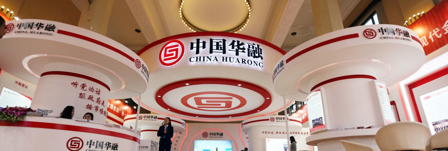 People visit the stand of China Huarong Asset Management Co. during an exhibition in Beijing