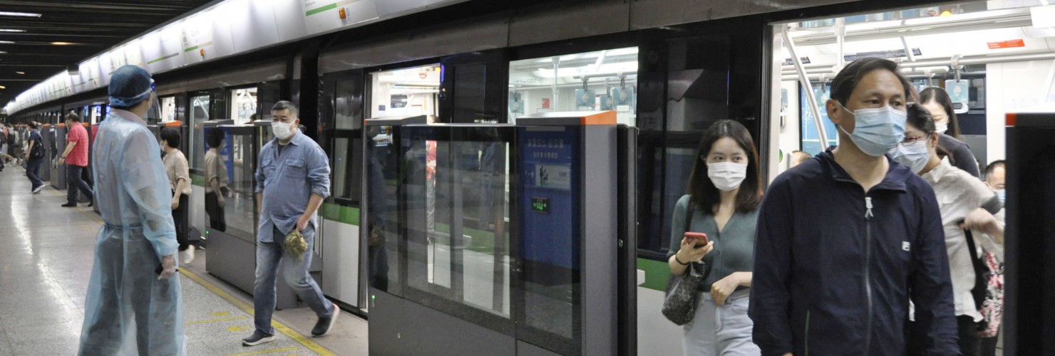 People wearing face masks get on and off a subway train in Shanghai, China