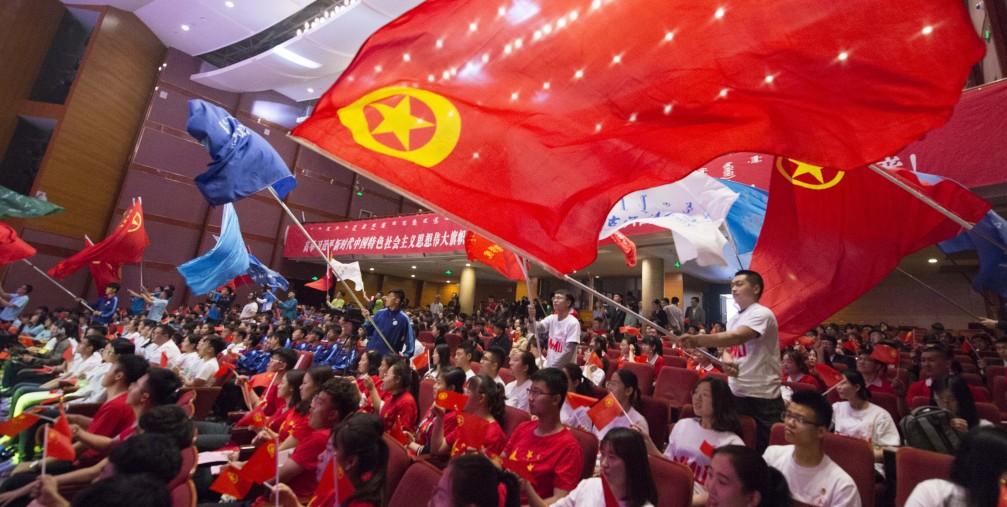 Young Chinese students from local universities wave flags of China and the Communist Youth League of China during a theme event to celebrate the upcoming 100th anniversary of the May Fourth Movement in Hohhot