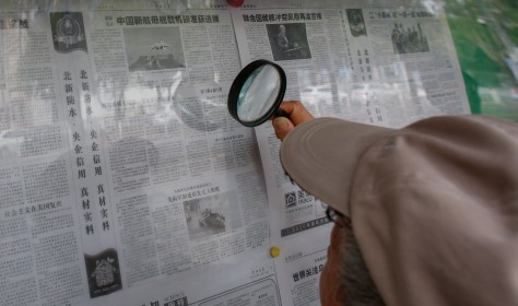 An elderly person reads a newspaper with magnifying glasses that says 'Progress made in the research and development of China's new aircraft carrier' in Beijing, China, 04 August 2022.
