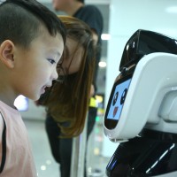 A boy looks at the intelligent robot "Xiaogui" at Yinghua Park metro station in Ningbo, Zhejiang Province.