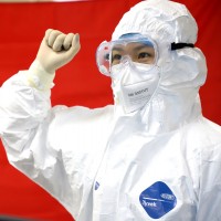 Chinese medical worker in front of a flag of the CCP