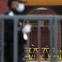Security guards stand guard at the closed gates of the Forbidden City
