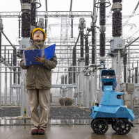 A robot assisted by power personnel makes a snowy inspection of a substation in Taizhou, Jiangsu province, China, December 18, 2023.