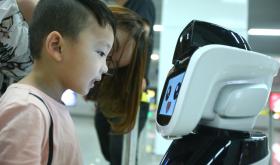 A boy looks at the intelligent robot "Xiaogui" at Yinghua Park metro station in Ningbo, Zhejiang Province.