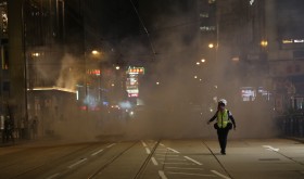 A journalist runs away from tear gas at Lan Kwai Fong, Hong Kong 
