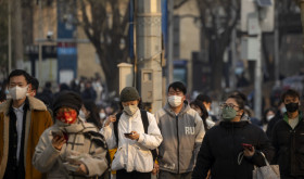 Commuters wearing face masks walk along a street during the morning rush hour in the central business district in Beijing, Thursday, Feb. 16, 2023.