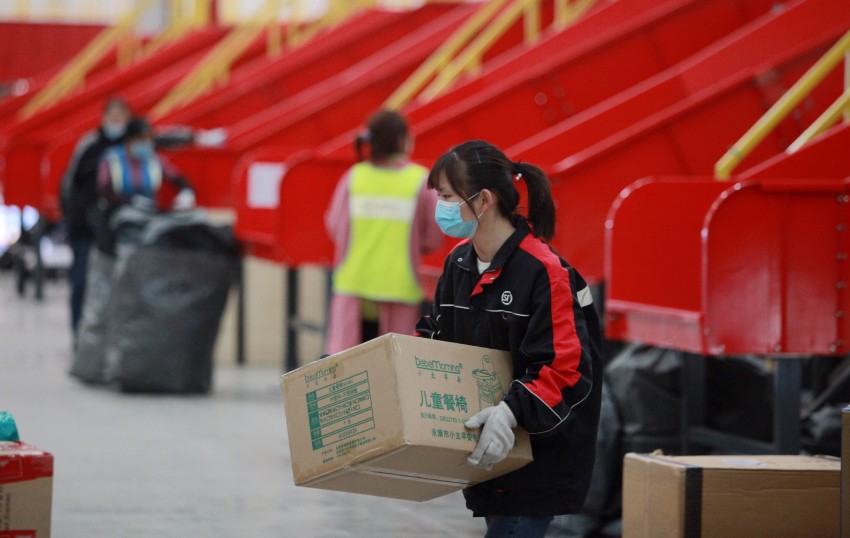 Workers sort packages at the transfer site of a Courier company in Guangling District, Yangzhou City